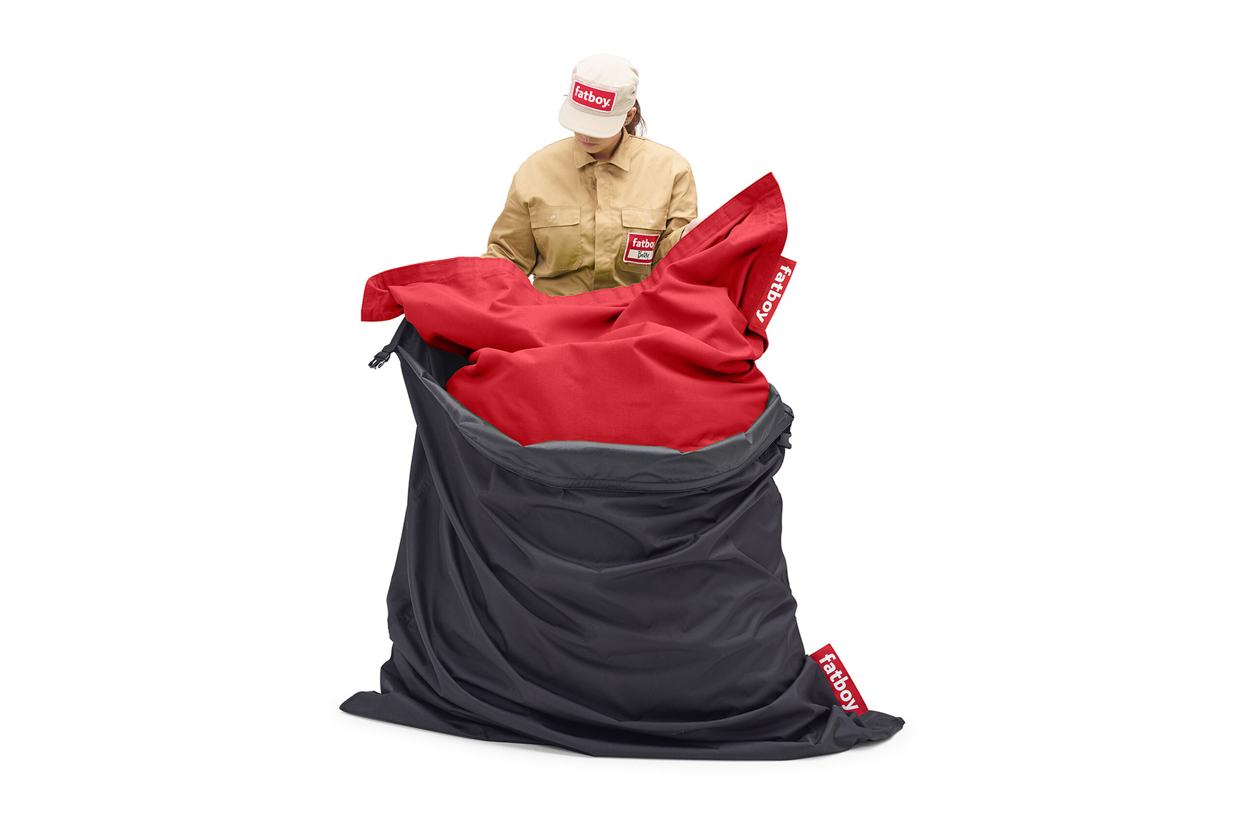 Person sitting with the red inner lining visible inside a dark gray Fatboy bean bag cover