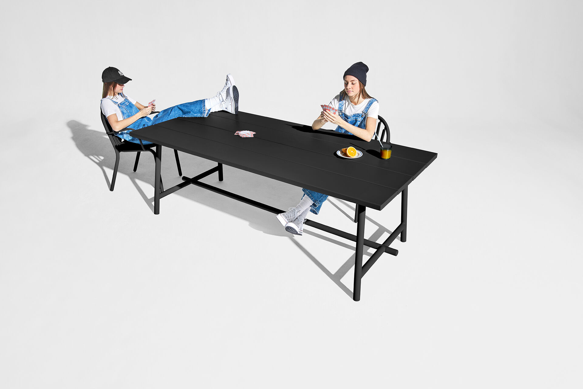 Two people sitting at a long table with drinks and food